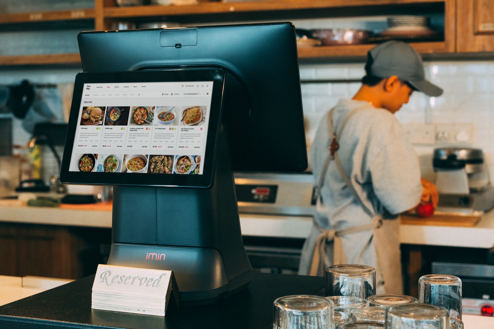 Digital kitchen order display beside a chef at work