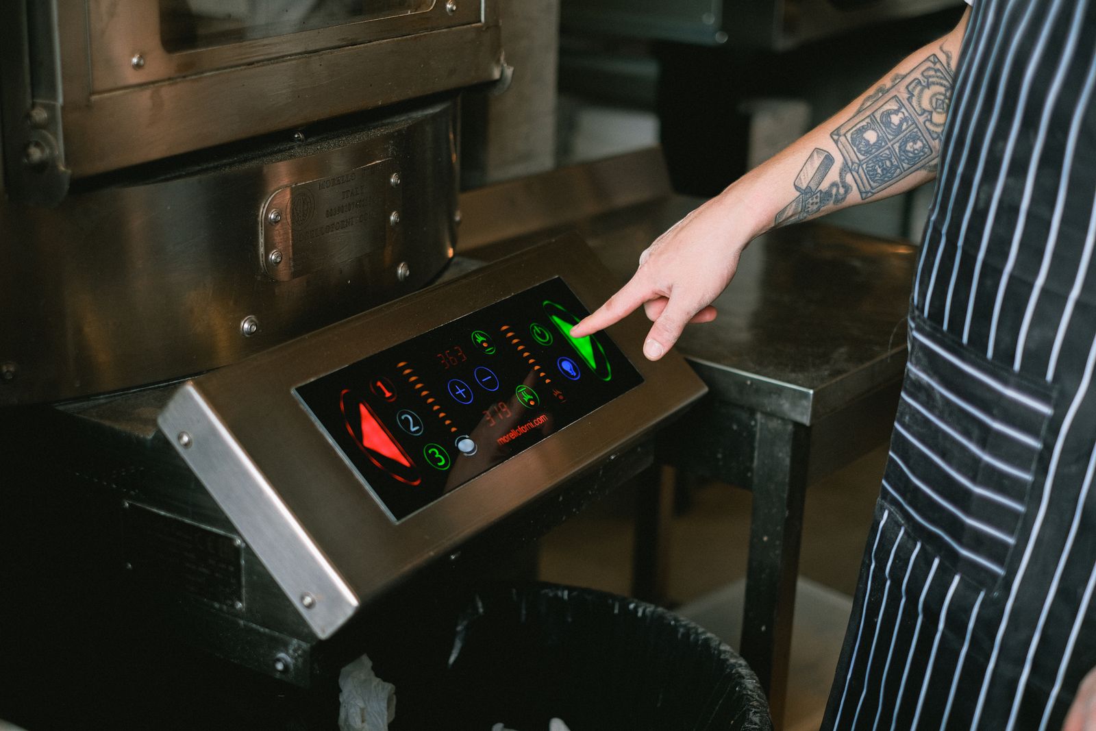 Chef operating a touchscreen control panel on modern kitchen equipment
