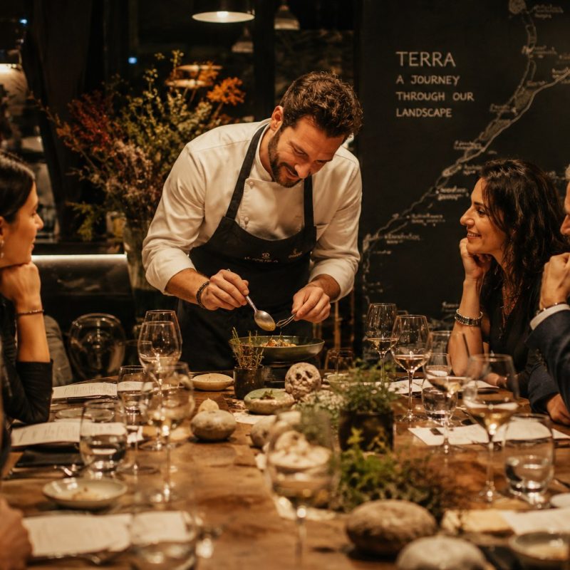 Chef-table dinner experience with intimate guest engagement, Terra map backdrop