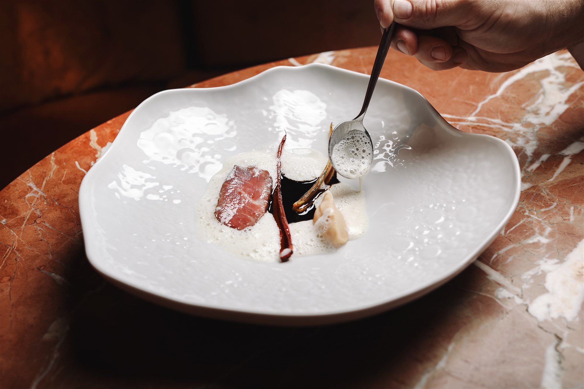 Plated dish at VIBE by Mattia Stanchieri being finished tableside