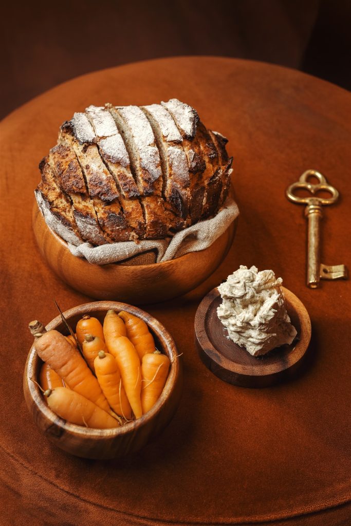 Generous simple food at Mattia Stanchieri's table — sourdough bread, baby carrots, and the VIBE key motif