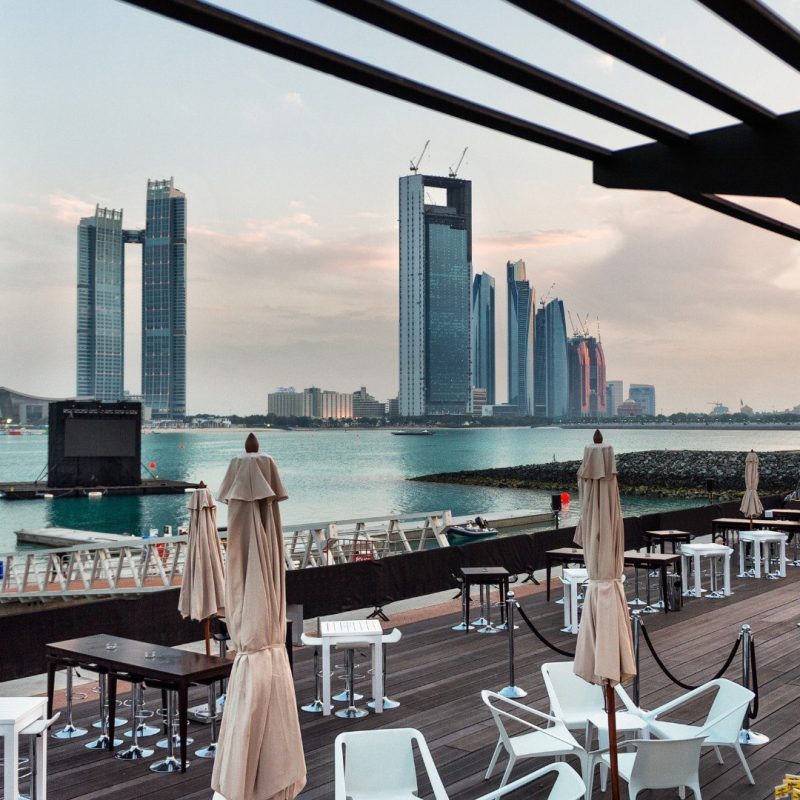 Waterfront restaurant terrace overlooking Abu Dhabi skyline at golden hour