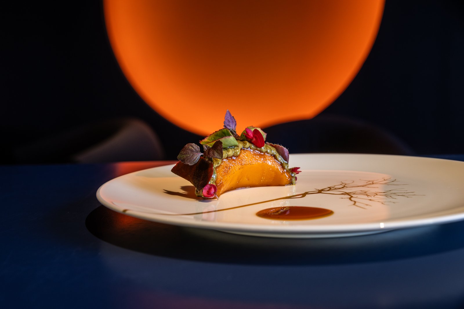 A plated dish at Agli Amici against a warm orange background.