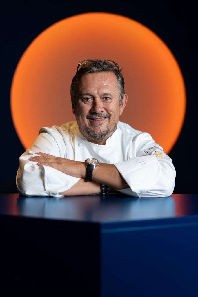 Chef Emanuele Scarello seated in his white chef jacket.