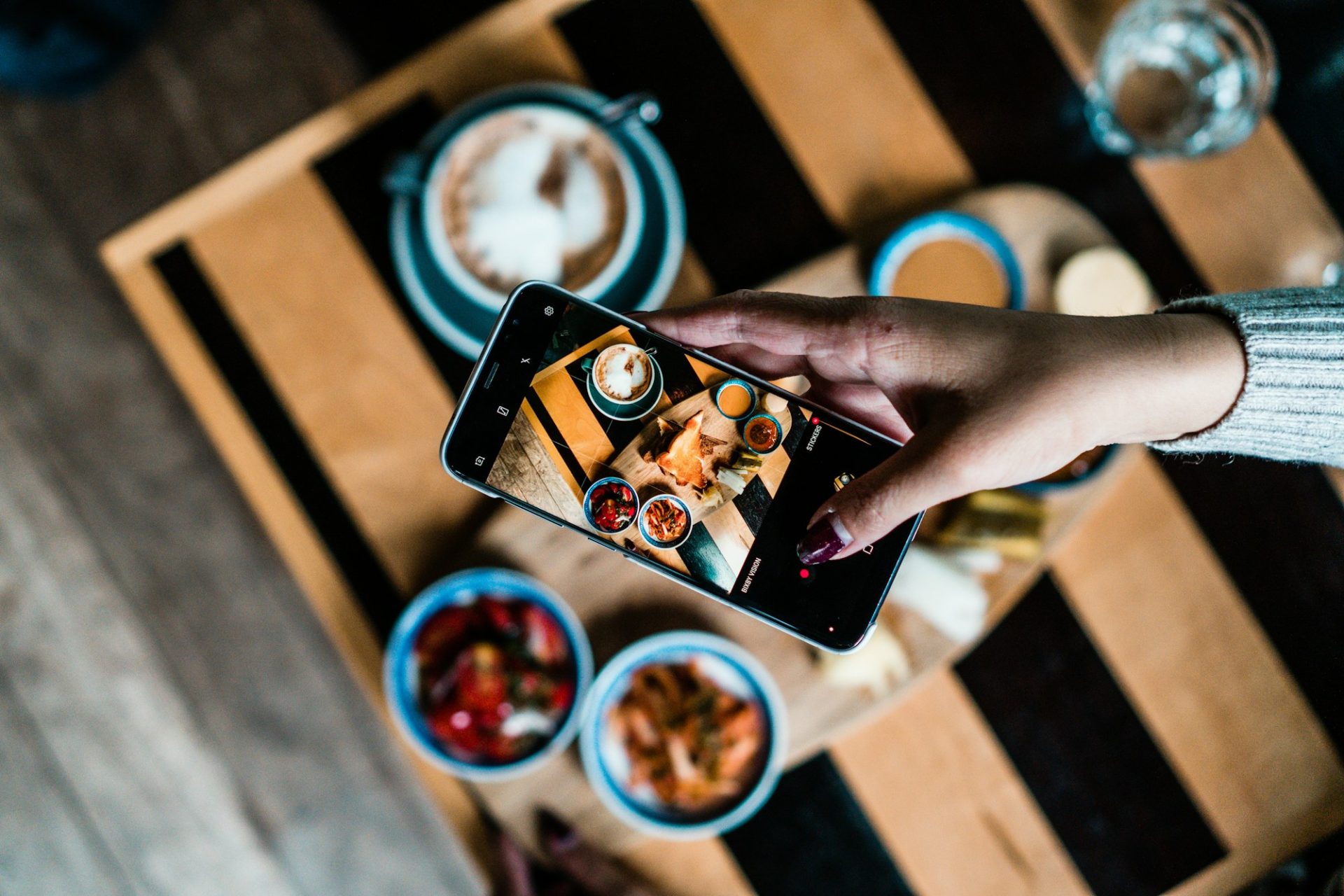 Diner photographing a table of dishes with a smartphone