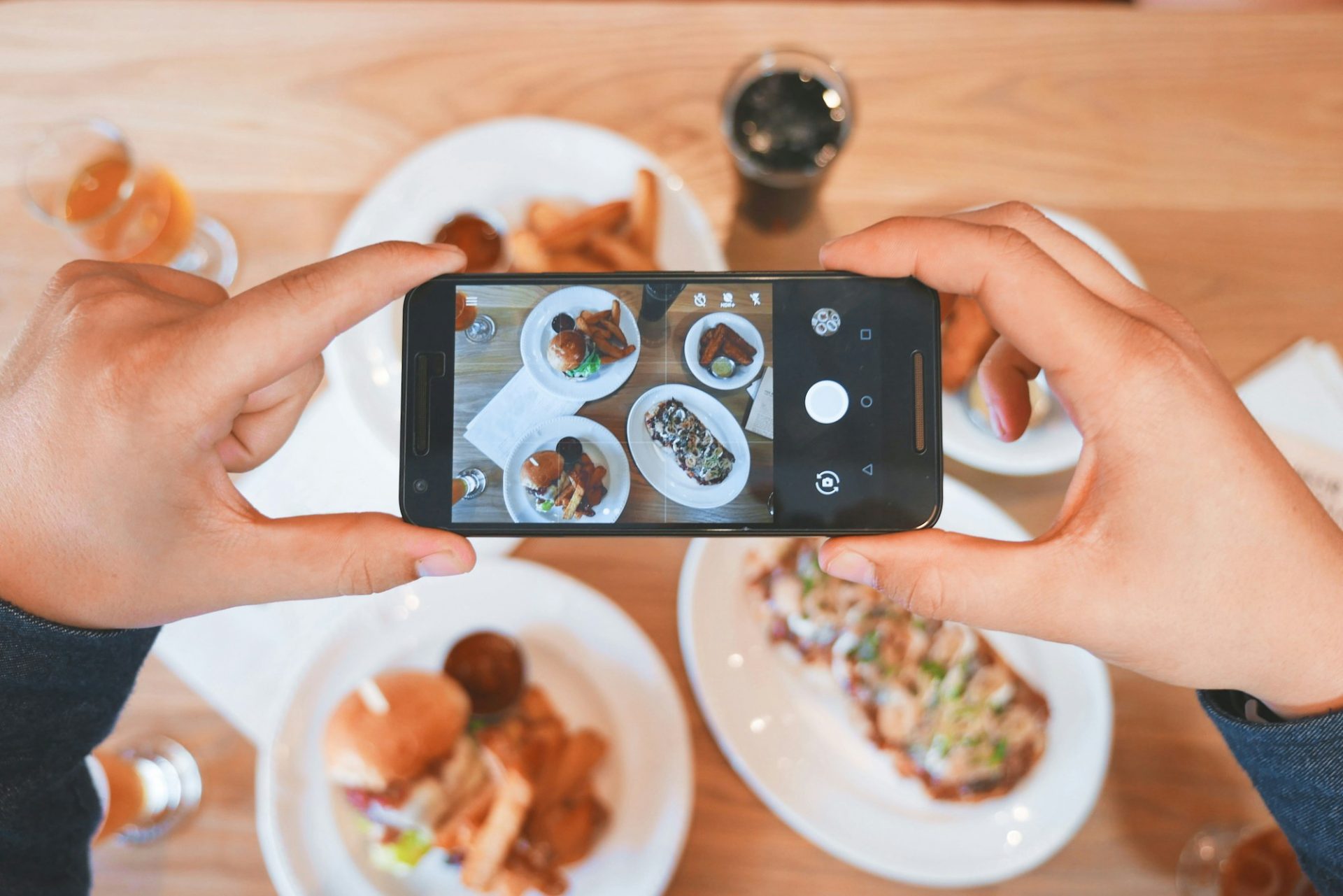 Guest filming restaurant plates on a smartphone from above
